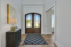 Modern home entryway with arched double doors, warm wood floors, and stylish contemporary decor.