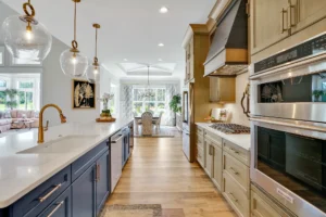 Modern navy and gold kitchen with white countertops, wood floors, and open dining area.