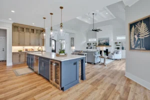 Modern coastal kitchen with blue island, beige cabinets, and open living space.