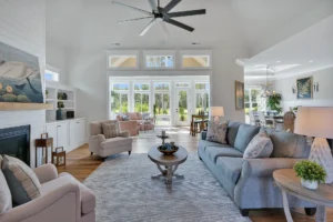 Bright modern living room with vaulted ceiling, gray sofa, fireplace, and natural light.