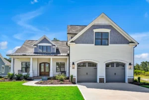 Modern white farmhouse with gray accents, front porch, double doors, and two-car garage.