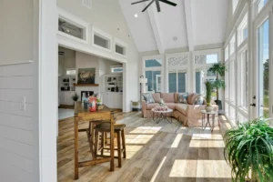 Bright modern rustic living room with large windows, light wood floors, and cozy beige sofa.