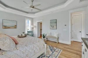 Bright coastal farmhouse bedroom with natural wood floors, soft gray walls, and serene beach decor.
