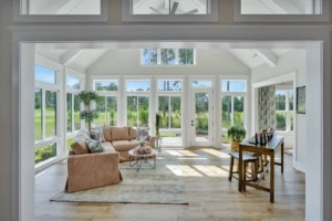 Bright airy sunroom with beige sofa, natural wood accents, and lush garden view.