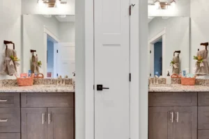 Modern double vanity bathroom with granite countertops, gray cabinets, and symmetrical elegant design.