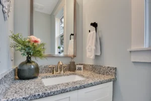 Elegant modern bathroom vanity with granite countertop, rustic mirror, and natural light.