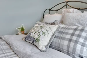 Cozy gray bedroom with vintage iron bed, layered pillows, and soft textured bedding.