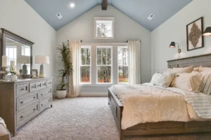 Rustic contemporary bedroom with vaulted blue ceiling, wooden accents, and cozy natural light design.