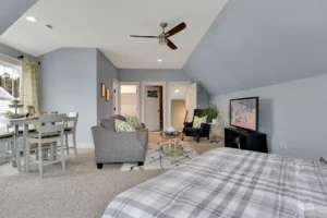 Bright attic bedroom suite with gray décor, cozy seating area, and natural light.
