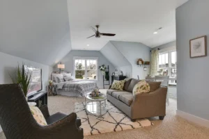 Modern bedroom suite with gray sofa, soft blue-gray walls, natural light, and elegant décor.