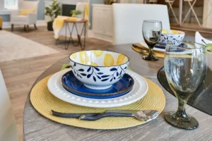 Modern dining table with lemon-patterned bowls, yellow placemats, and elegant contemporary décor.