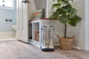 Modern farmhouse entryway with white bench, wood accents, rain boots, and potted plant.