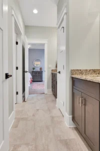 Bright modern hallway with granite countertop, white doors, and elegant beige tile flooring.