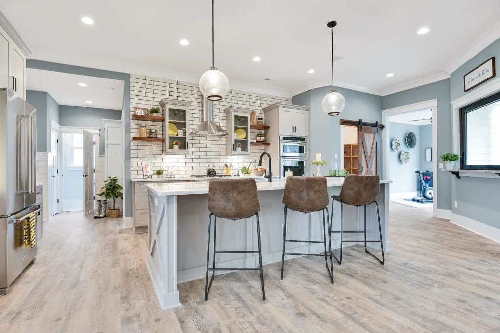 Bright modern kitchen with white island, open shelving, stainless appliances, and natural light.