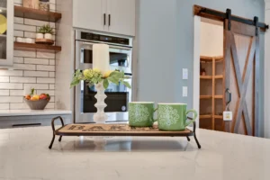 Modern farmhouse kitchen with white cabinets, wood accents, island tray decor, and barn door.