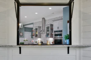 Modern farmhouse kitchen with granite pass-through, white shiplap walls, and stainless-steel appliances.