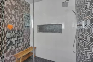 Modern glass shower with geometric hex tiles, chrome fixtures, and a stylish recessed niche.