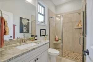 Modern beige tile bathroom with glass walk-in shower and light stone vanity countertop.