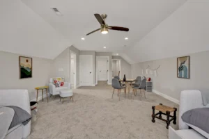 Bright modern attic bonus room with gray decor, cozy seating, and multipurpose living space.