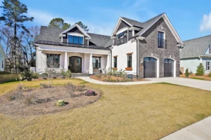 Modern suburban home with brick and siding exterior, columns, dormer windows, and two-car garage.