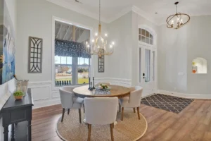 Bright open-concept dining room with wooden table, beige chairs, and modern chandelier.