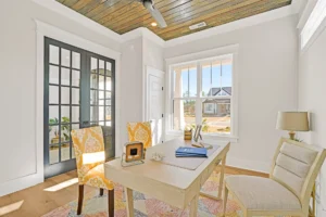 Bright modern home office with natural light, wooden ceiling, stylish chairs, and sunny suburban view.