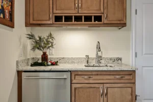 Small kitchenette with wooden cabinets, granite countertop, wine rack, and modern stainless steel fixtures.