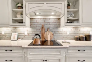 Elegant white kitchen with copper kettle, warm lighting, and rustic wooden accents.
