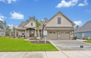 Modern tan Craftsman home with porch and manicured lawn in sunny Wilmington, North Carolina.