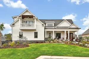 Modern white farmhouse with gabled roof, dark shingles, and inviting front porch under blue sky.