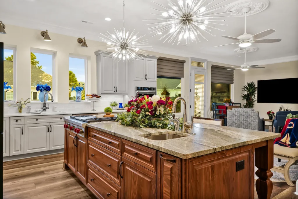 Modern kitchen with dark wood island, granite countertop, and elegant lighting fixtures.