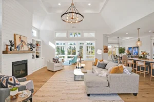 Bright modern farmhouse living room with vaulted ceilings, gray sectional, shiplap fireplace, and natural light.
