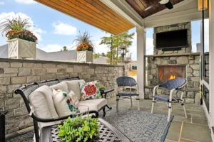 Cozy outdoor patio with stone fireplace, modern seating, and warm wooden ceiling for relaxing evenings.