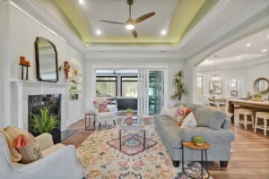 Bright open-concept living room with fireplace, neutral decor, natural light, and modern ceiling fan.