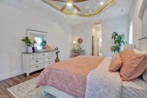 Modern coral bedroom with tray ceiling, white dresser, and cozy contemporary decor.