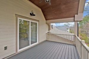 Modern covered balcony with gray composite decking, wood ceiling, and beige siding in Wilmington.