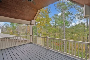 Covered outdoor deck with wood ceiling and forest view offering cozy, rustic outdoor living space.