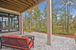 Modern patio with wooden ceiling, orange cushions, and scenic woodland view for relaxing outdoors.