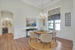 Elegant dining room with round wooden table, beige chairs, and warm neutral modern decor.