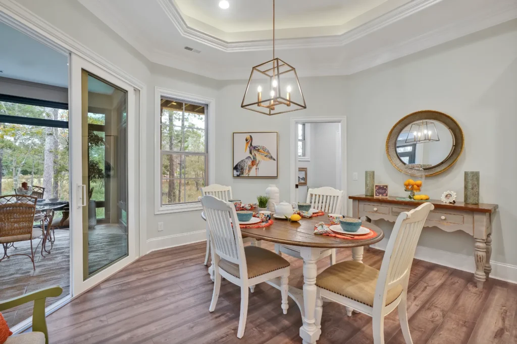 Bright modern dining room with white table, gold light fixture, and natural wood accents.
