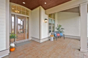 Modern front porch with glass door, cozy bench, autumn accents, and welcoming home entryway.