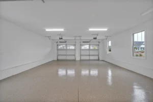 Bright modern two-car garage with epoxy floor, white walls, and ample natural light.