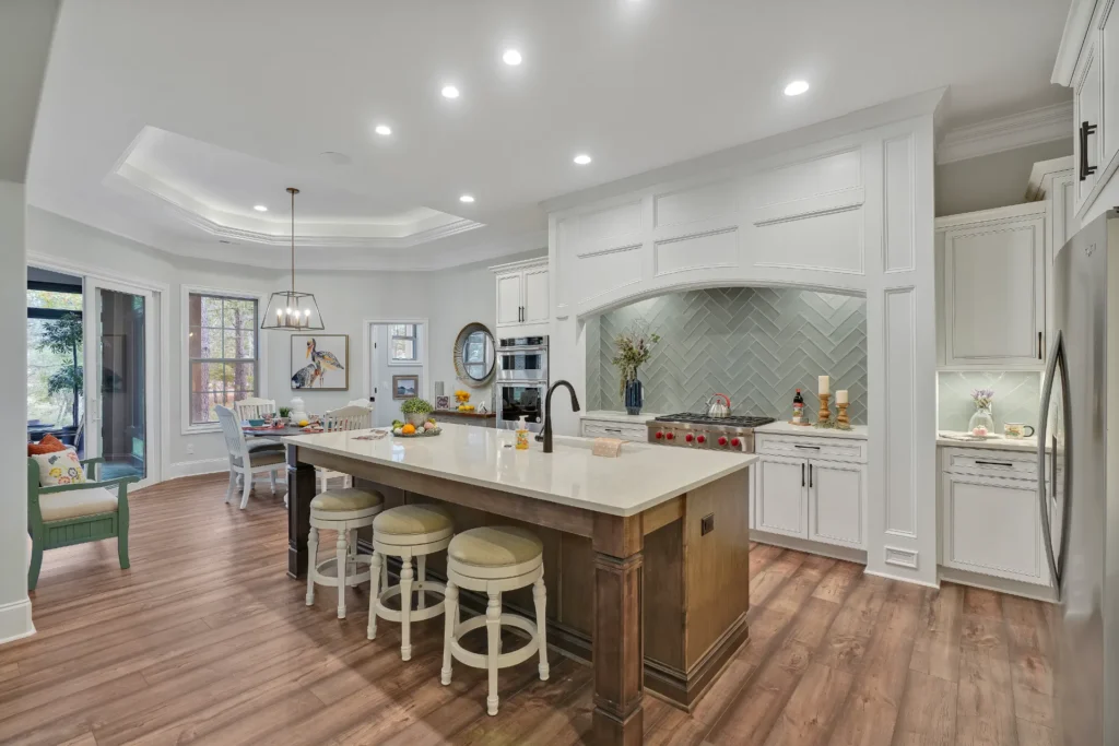 Bright modern kitchen with white cabinets, wood island, stainless appliances, and warm hardwood floors.
