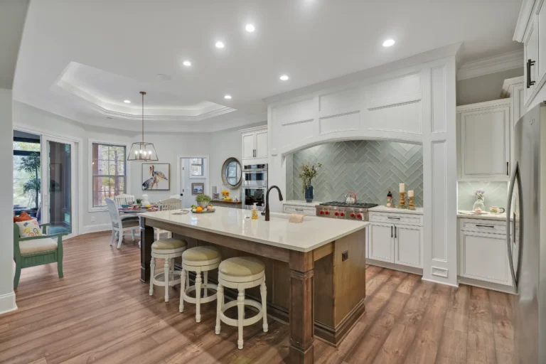 Bright modern kitchen with white cabinets, wood island, stainless appliances, and warm hardwood floors.