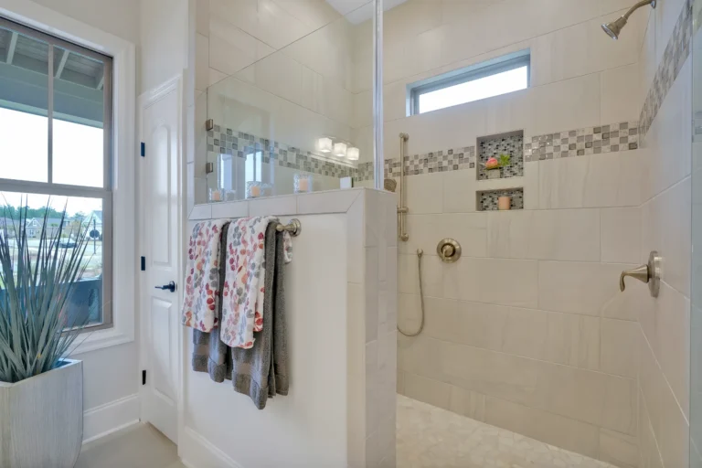 Modern beige walk-in shower with glass enclosure, mosaic tiles, and natural light spa ambiance.