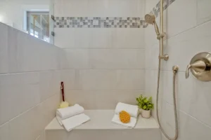 Modern walk-in shower with beige tiles, mosaic accent, built-in bench, and spa-inspired decor.