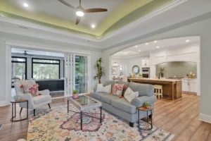 Modern open-concept living room and kitchen with gray sofa, wood island, and natural lighting.