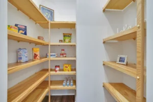 Bright modern pantry with light wood shelves, white walls, and minimal organized décor.