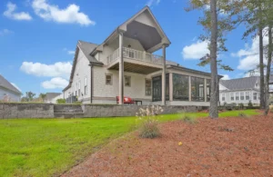 Modern two-story suburban home with covered patio, upper balcony, and landscaped backyard.