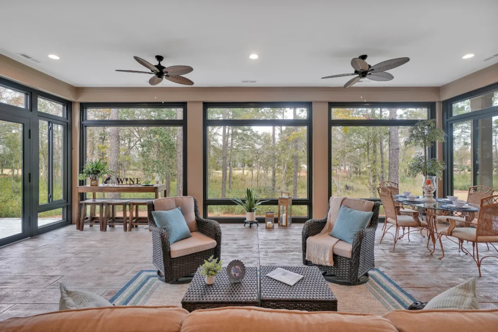 Airy sunroom with wicker furniture, large windows, and wooded views for relaxing and dining.